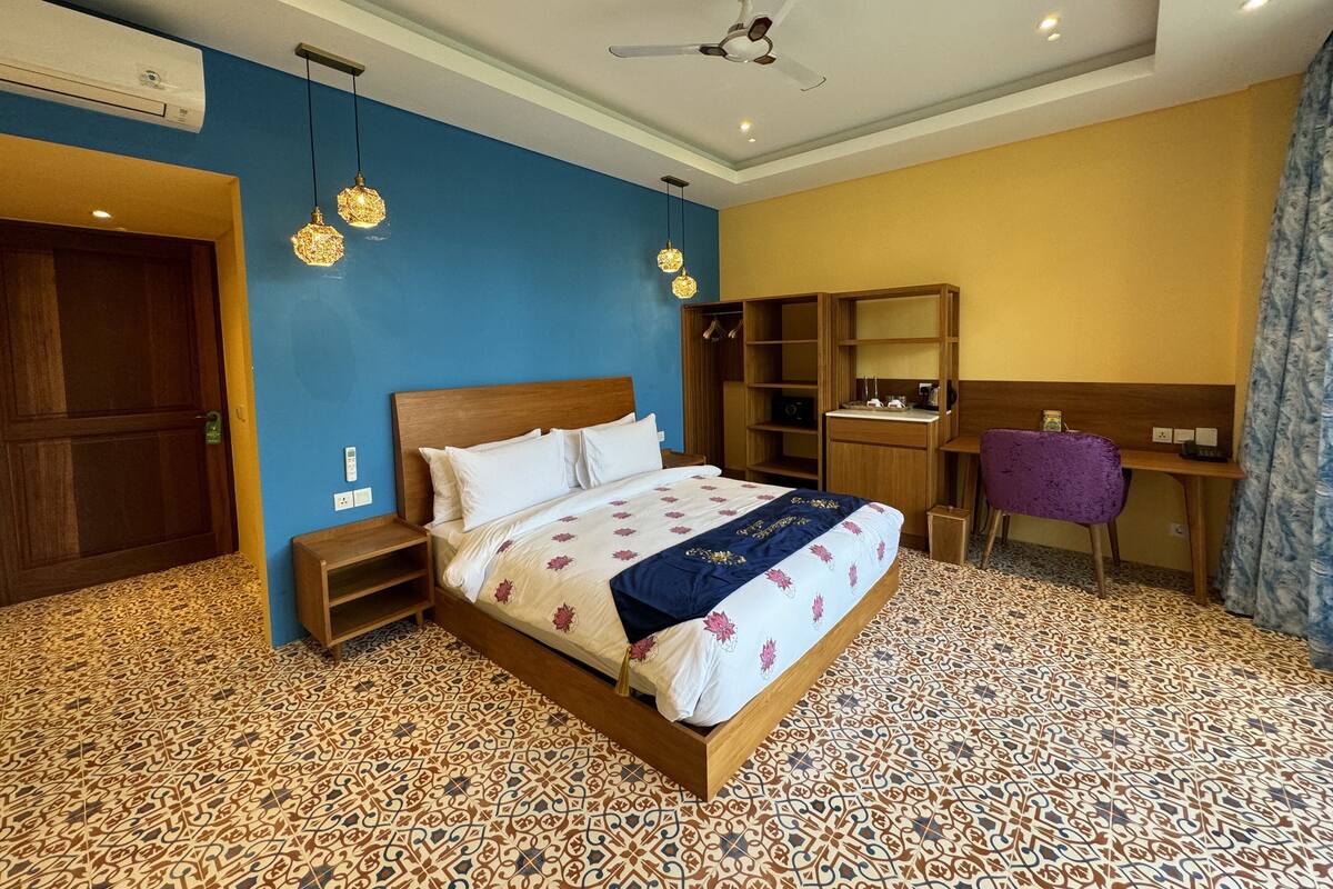 Quarto com cama, guarda-roupa, escrivaninha e ventoinha no teto.