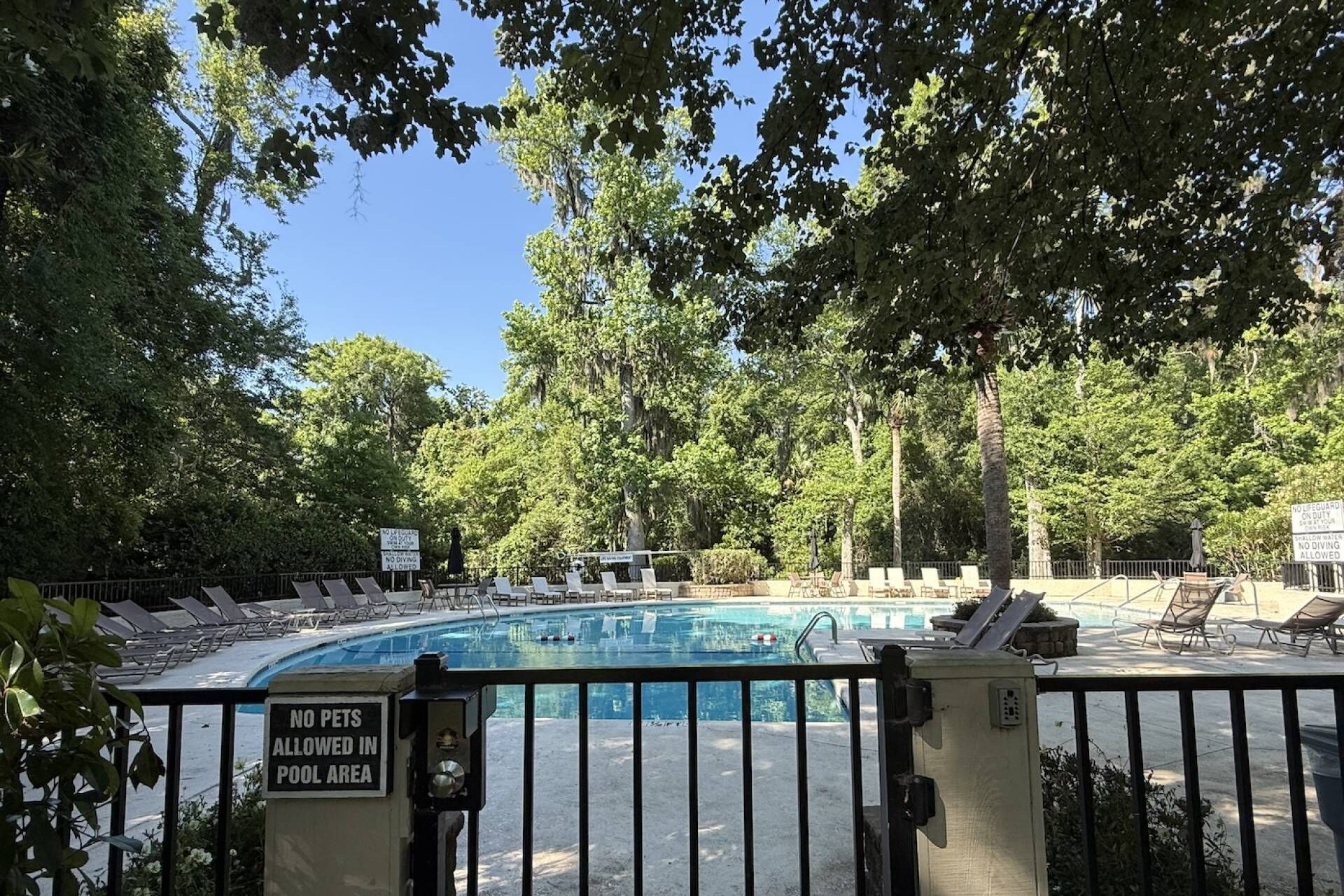 A pool area with lounge chairs and a sign prohibiting pets.
