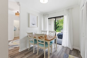 Un coin repas avec une table et des chaises, un tableau encadré au mur et une vue par la fenêtre.