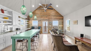 A spacious kitchen with a long island, bar stools, and a dining area with wicker chairs and a wooden table. - 2 Waterfront Homes w/ Views, Pool, Boat Dock | Laguna Village Oasis by AvantStay (Corpus Christi)