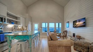 A spacious living area with a kitchen, a large window with a view, and a cozy seating arrangement.