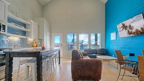 Amplia sala de estar con cocina, un sofá marrón y una mesa de comedor con sillas.
