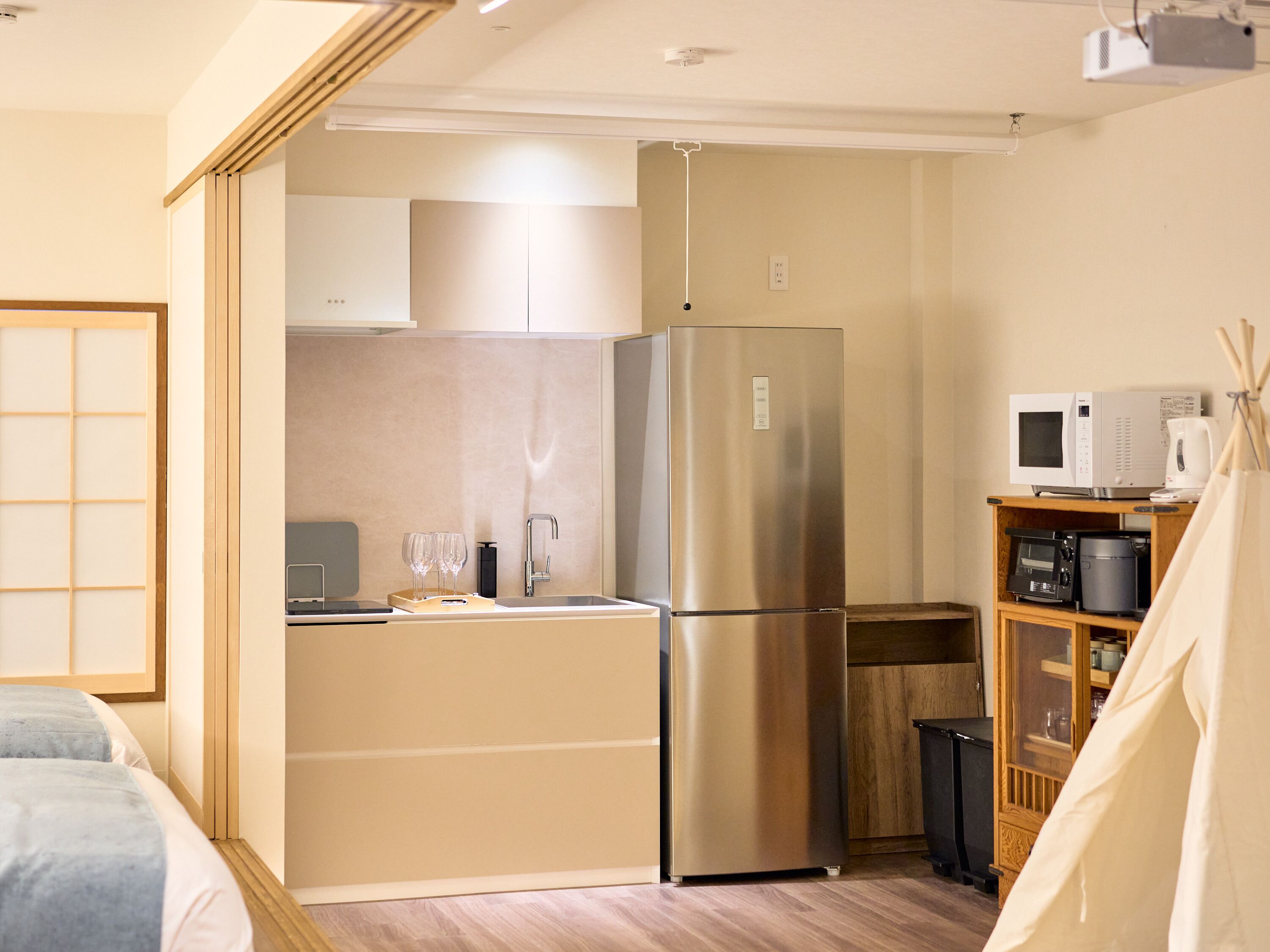 Cocina compacta con refrigerador, microondas y un mueble pequeño.
