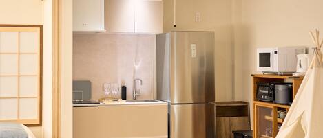 Cocina compacta con refrigerador, microondas y un mueble pequeño.