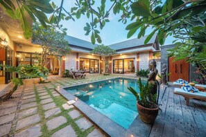 A pool area with a stone pathway, lounge chairs, and a statue. - Villa Jonsu Uluwatu by Nagisa Bali (Ungasan)
