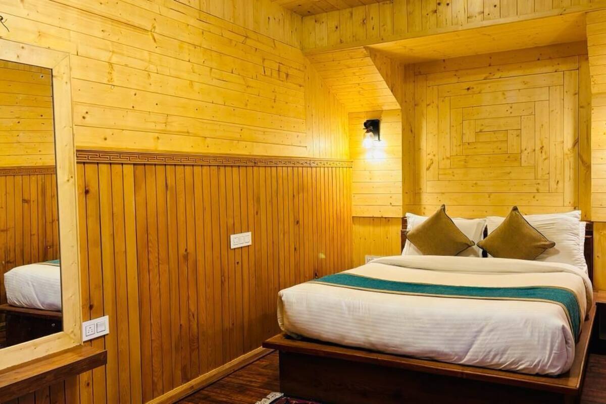 Een kamer met houten lambrisering, een bed, een spiegel en twee wandlampen.