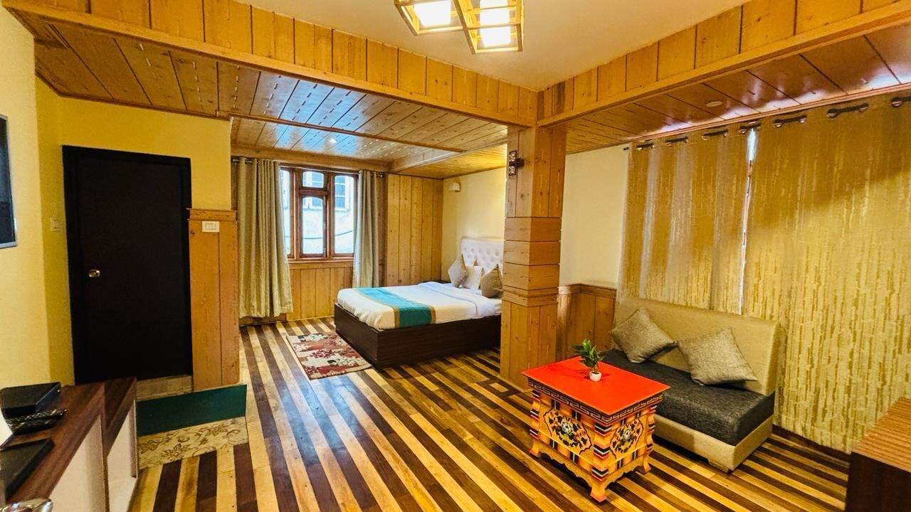 Una habitación con piso de madera, una cama, un sofá, una mesita y una puerta.