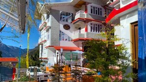 A multi-story building with balconies, a sign indicating a restaurant, and a mountainous backdrop.
