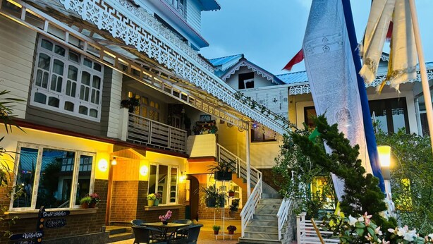 A traditional building with a balcony, outdoor seating, and a staircase leading to an upper level.