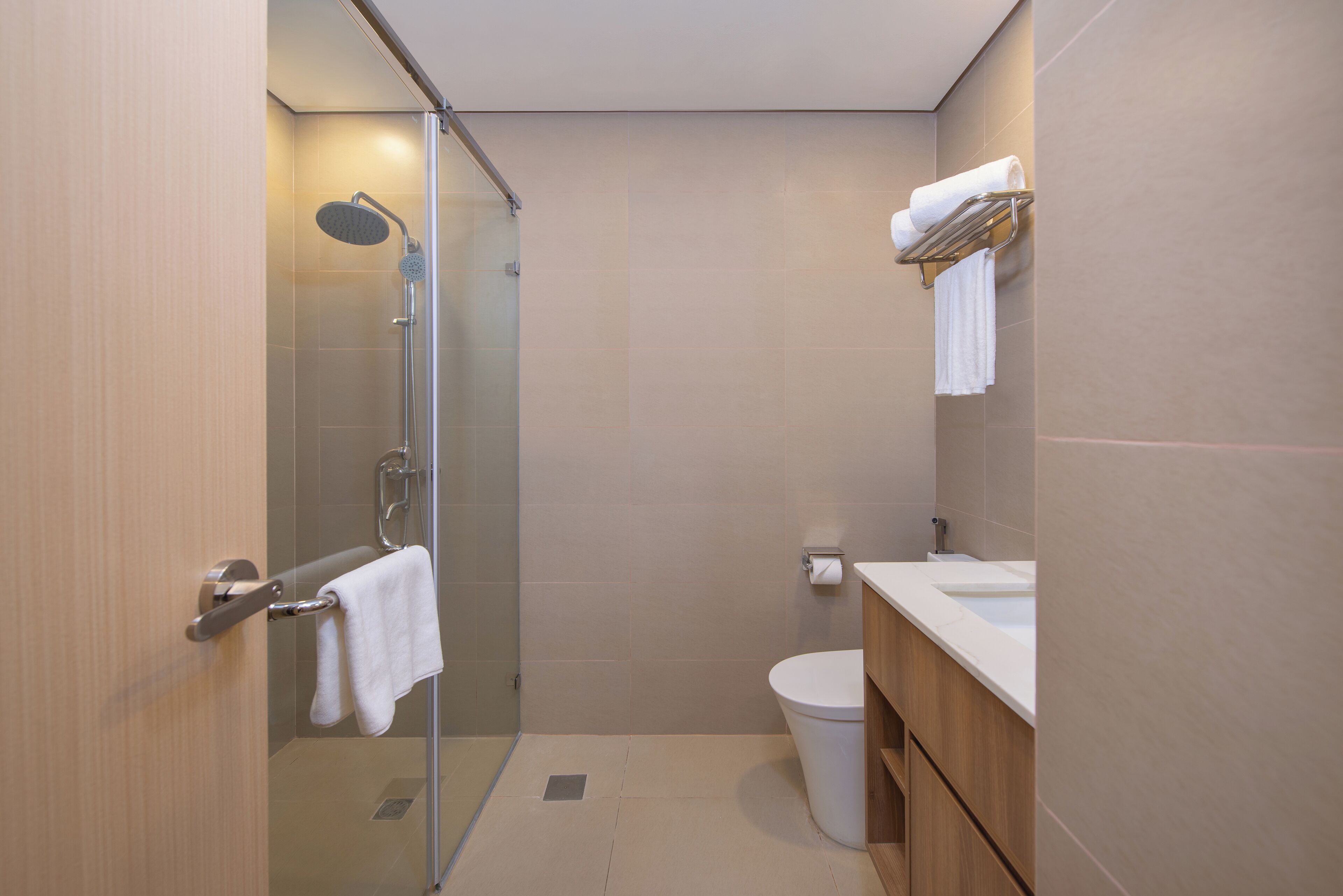 A modern bathroom with a glass-enclosed shower, a toilet, and a sink with a wooden vanity.