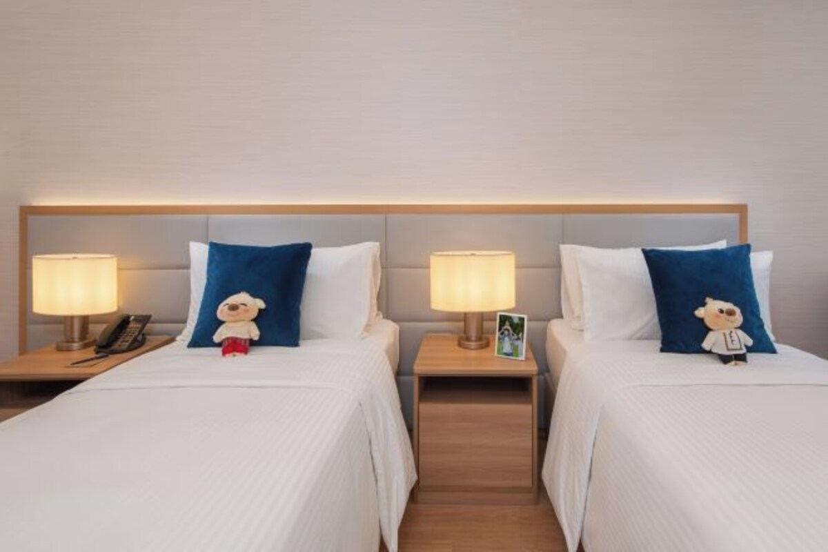 Two single beds with headboards, bedside lamps, and small teddy bear decorations.
