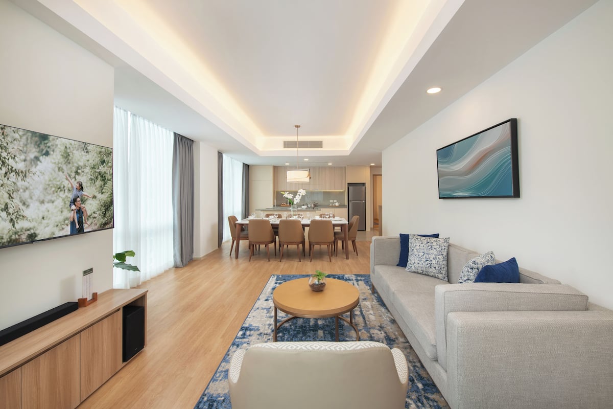Uma sala de estar moderna com sofá, mesa de centro, televisão e área de jantar.