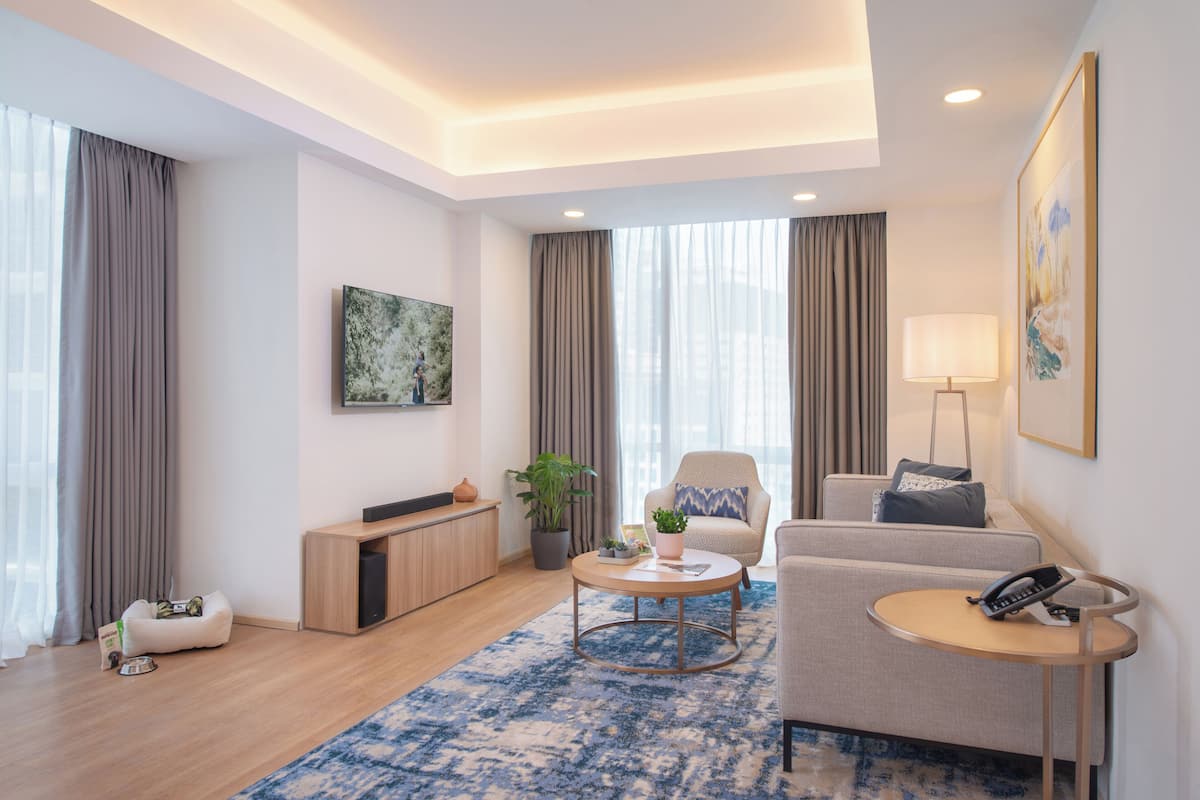 Uma sala de estar moderna com sofá, poltrona, mesa de centro e uma pequena mesa lateral com um telefone.