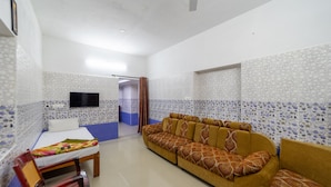 Una habitación con sofá, cama, televisor y un papel tapiz estampado.
