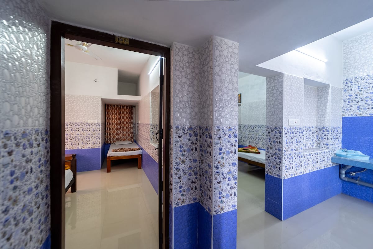 A room with a bed, a bathroom with a sink, and a shower area.
