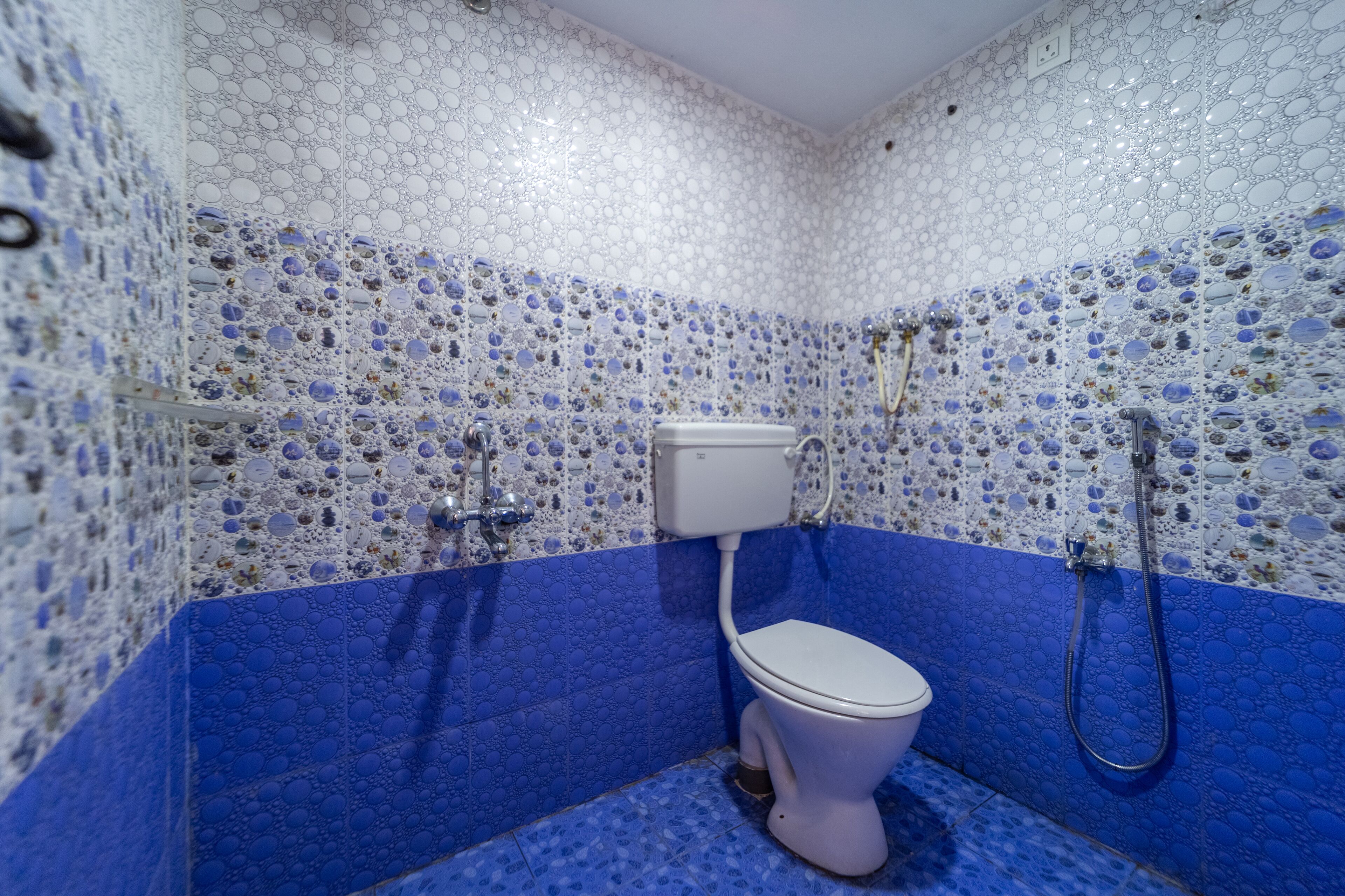 A bathroom with a mosaic tile wall and floor, a toilet, and a shower.