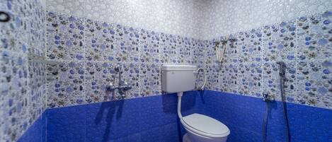 A bathroom with a mosaic tile wall and floor, a toilet, and a shower.