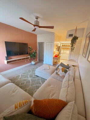 A living room with a flat-screen TV, a ceiling fan, a sofa, and a dining area with a table and chairs. - Central cozy 2BR/2BA condo w/ dedicated workspace (Miami)