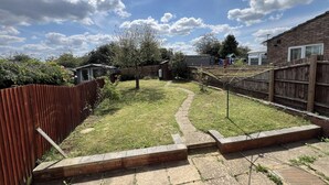 A backyard with a wooden fence, a brick pathway, and a small shed. - 3-bed House Sleeps 5 - Smart Tv - Free Parking (Leighton Buzzard)