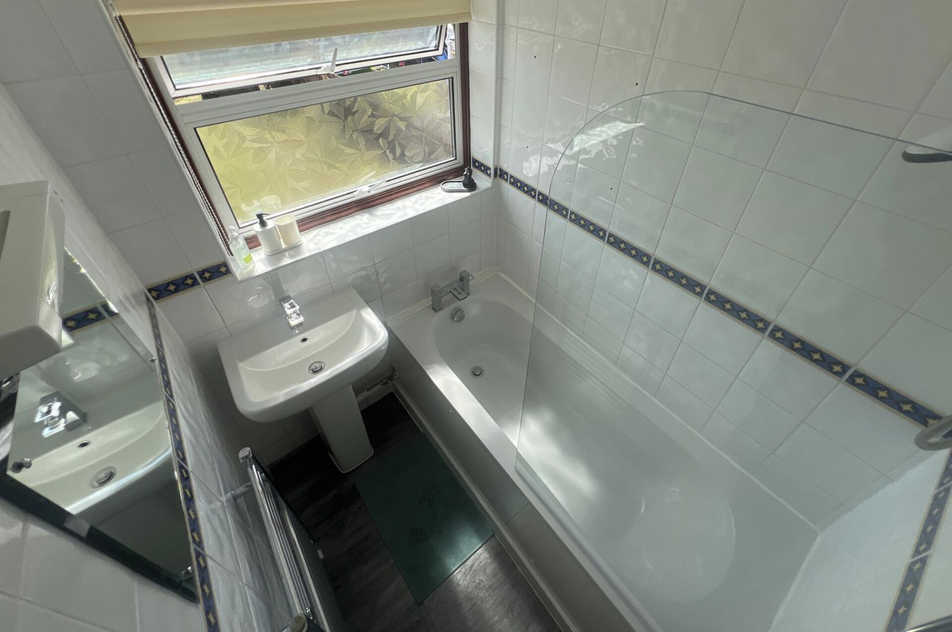 A bathroom with a sink, bathtub, and window.
