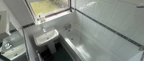 A bathroom with a sink, bathtub, and window.