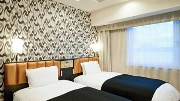 A hotel room with two beds, a control panel, a wall with a wavy pattern, and a window with curtains.