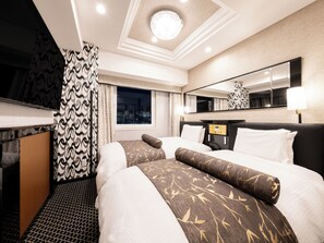 Habitación de hotel con dos camas, un espejo grande, una ventana con vista a la ciudad e iluminación empotrada en el techo.