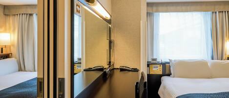 Una habitación de hotel con cama, escritorio, teléfono, espejo y ventana con cortinas.