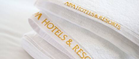 A stack of white towels with embroidered text reading "AAA HOTELS & RESORTS".