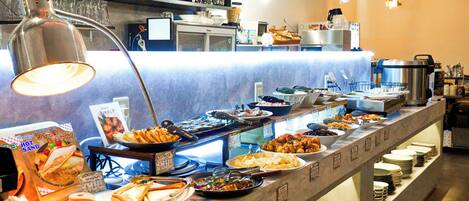 A buffet setup with various food items and a counter with plates and utensils.