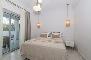 Ein Schlafzimmer mit einem Bett, einem Nachttisch und einer Schiebetür zu einem Außenbereich.