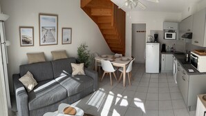 Un espace de vie compact comprenant un canapé, une table à manger et un coin cuisine.