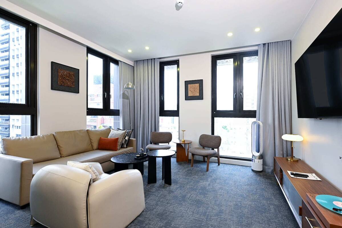 A modern hotel room with a sofa, armchair, and a small table.