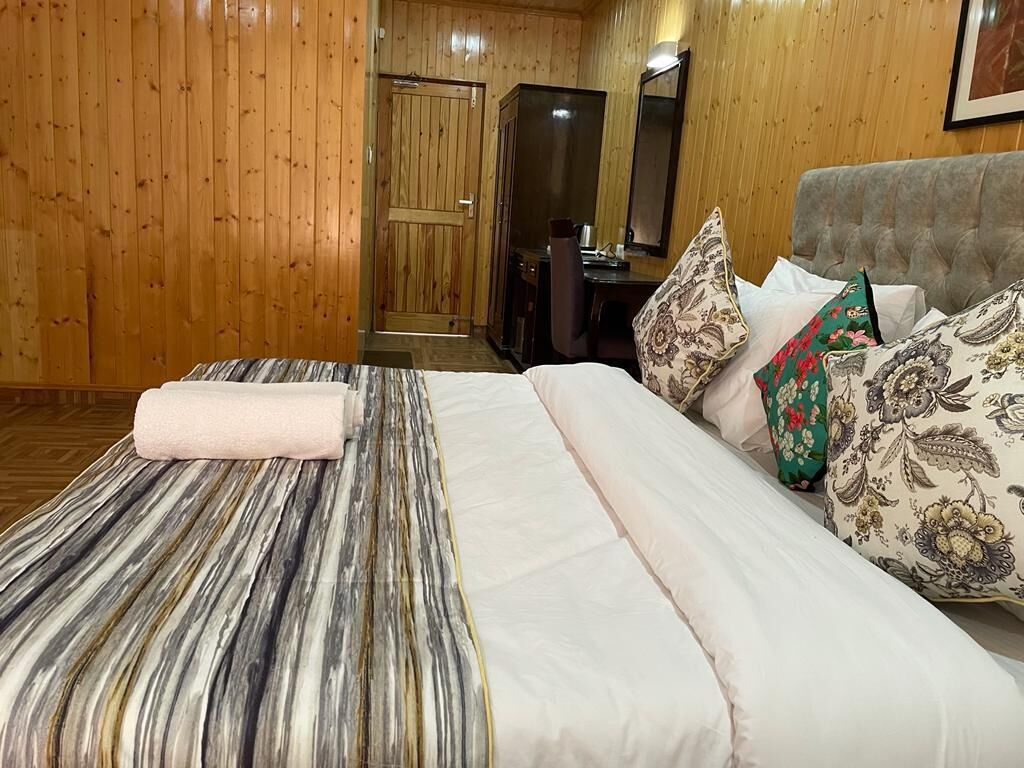 A hotel room with a bed, a desk, and a mirror.