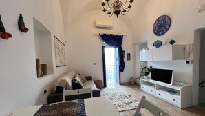 Ein Wohnzimmer mit Esstisch, Sofa, Fernseher und einer Kandelaber.