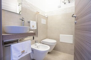 Bathroom features a large vessel sink, compact bidet, and standard toilet.