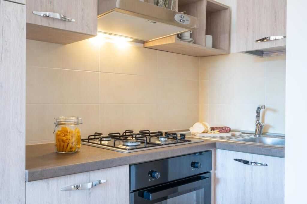 A modern kitchen with a gas stove, a built-in oven, and a stainless steel sink.