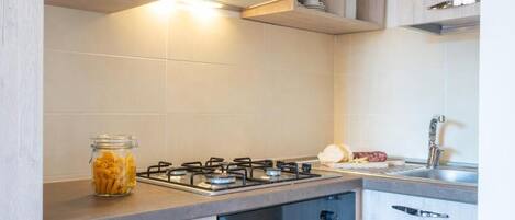 A modern kitchen with a gas stove, a built-in oven, and a stainless steel sink.