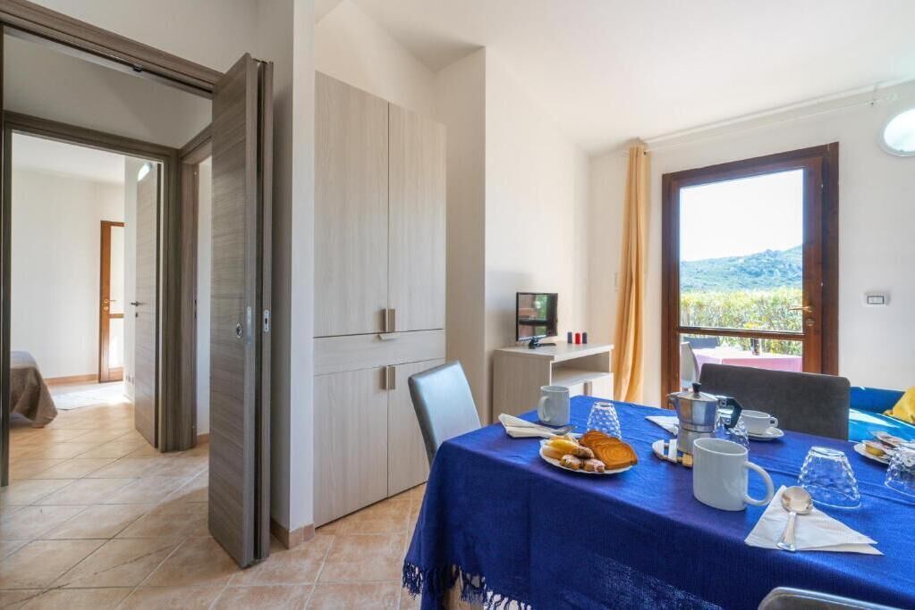 A dining area with a table set for two, a coffee machine, and a view of the outdoors.