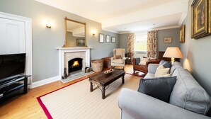 A living room with a fireplace, a sofa, a television, and a lamp. - Westerpark Countryside Cottage Aswanley Aberdeenshire (Huntly)
