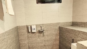 Une petite salle de bain carrelée, équipée de toilettes, d’un lavabo et d’un miroir.