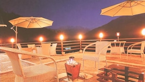 Un espace extérieur aménagé avec des chaises et des tables en osier, un foyer et des parasols.