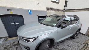 A silver SUV parked in a driveway with a garage door and a blue parking sign. - Ferienwohnung Kellermeister für 4 Personen in den Ferienwohnungen Bullay, Mosel (Bullay)