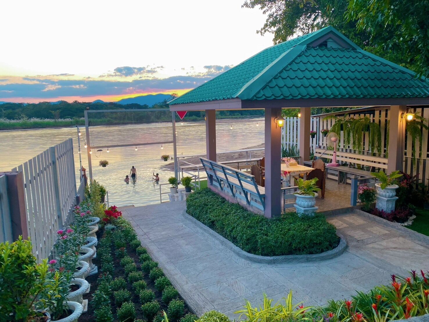 A riverside gazebo with a view of the river, outdoor seating, and potted plants.