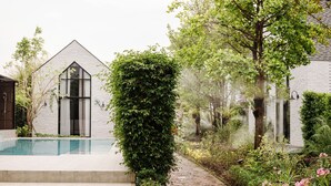 A modern house with a swimming pool, a garden with various plants, and a brick pathway. - Phuping Valley Resort  (Tak)