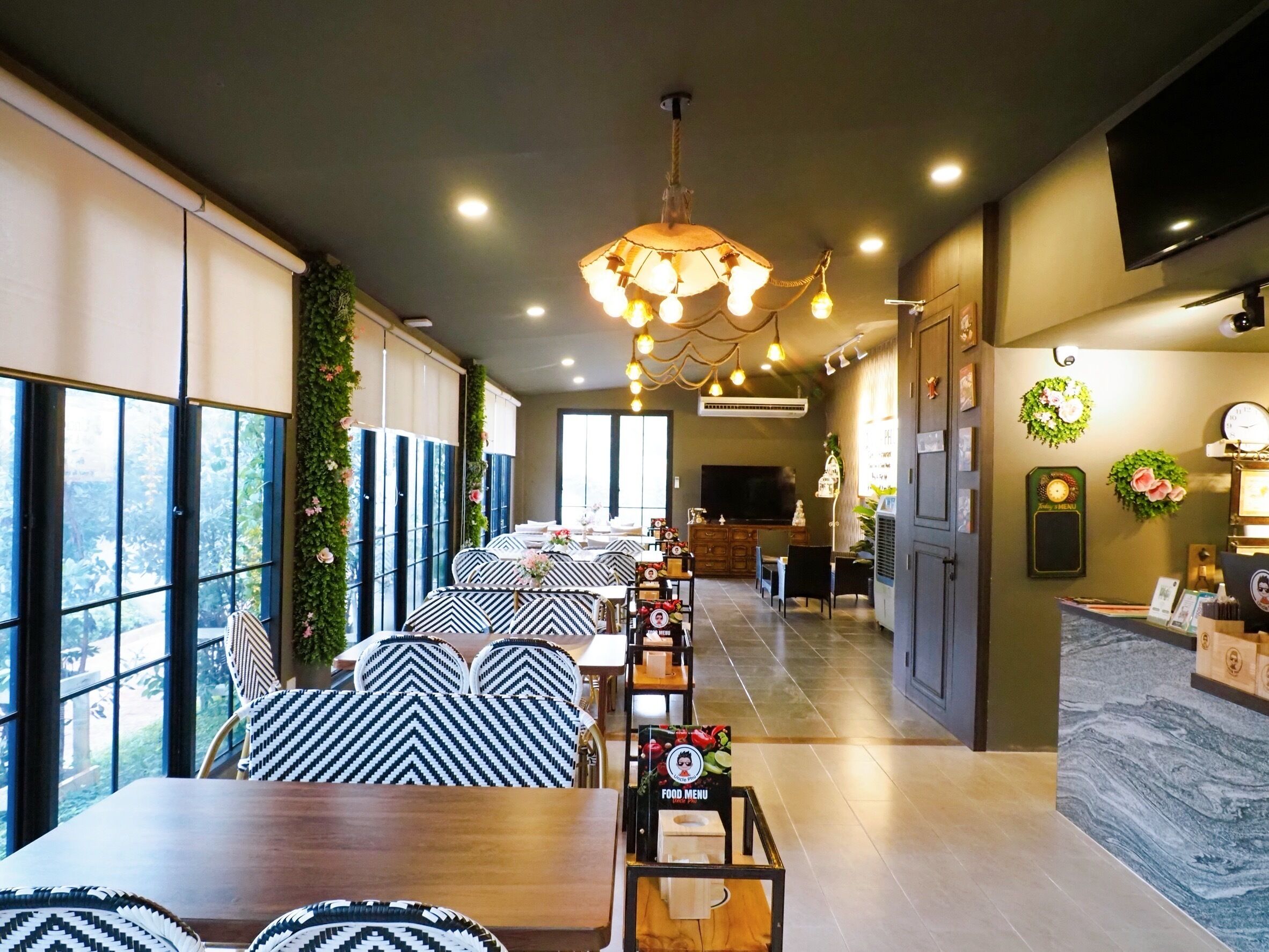 A modern dining area with a long table, chairs, and a chandelier.