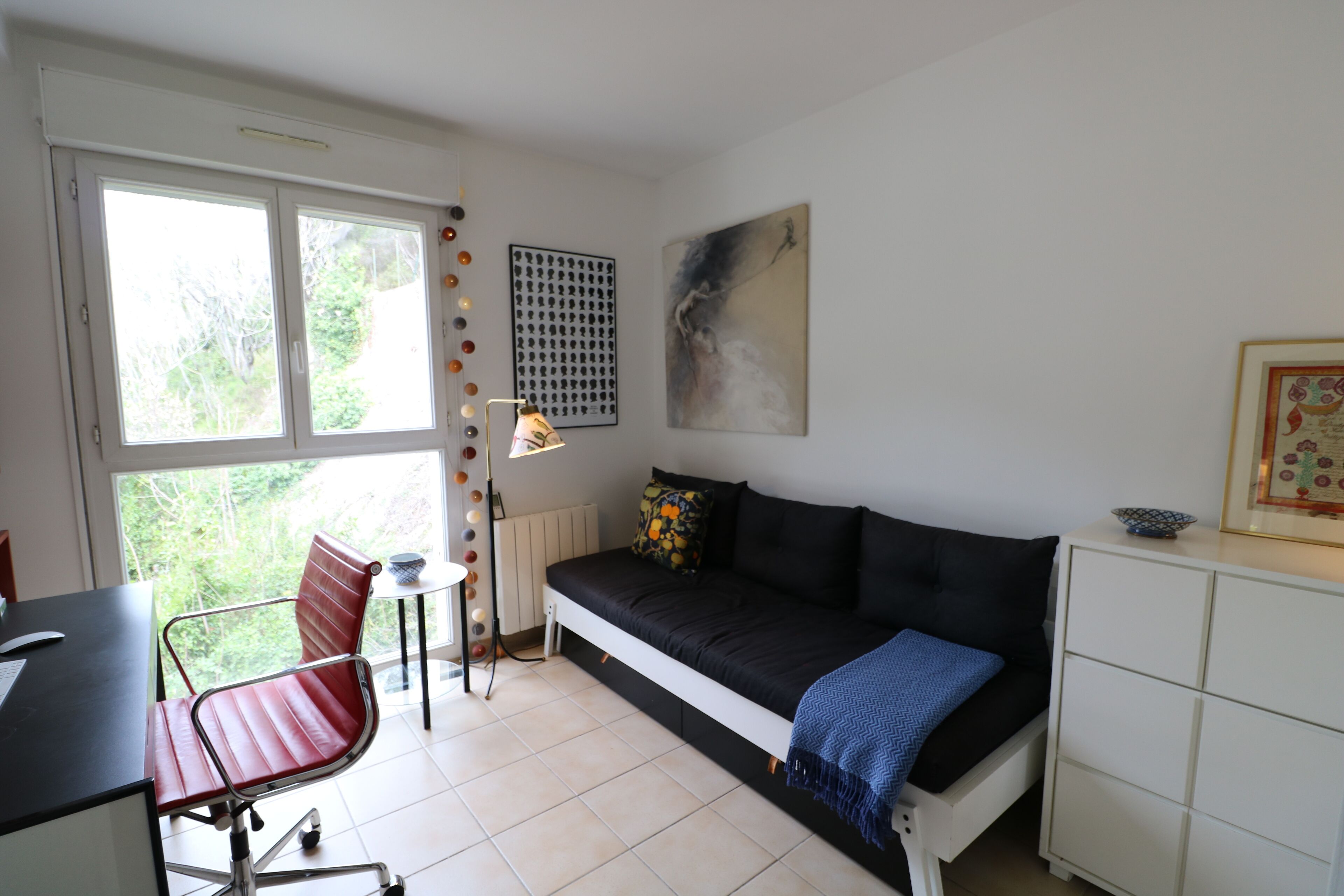 Een kamer met een bed, bureau, stoel en radiator.