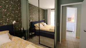 A bedroom with a bed, a nightstand, a mirror, and a door leading to another room. - Lovely apartment with AC and a large terrace - pool in the residence. (Nice)