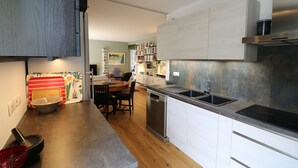A modern kitchen with a dishwasher, sink, and a dining area with a table and chairs. - Lovely apartment with AC and a large terrace - pool in the residence. (Nice)