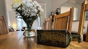 Ein Holztisch mit einer Glasvase voller Blumen und einer alten Flasche.